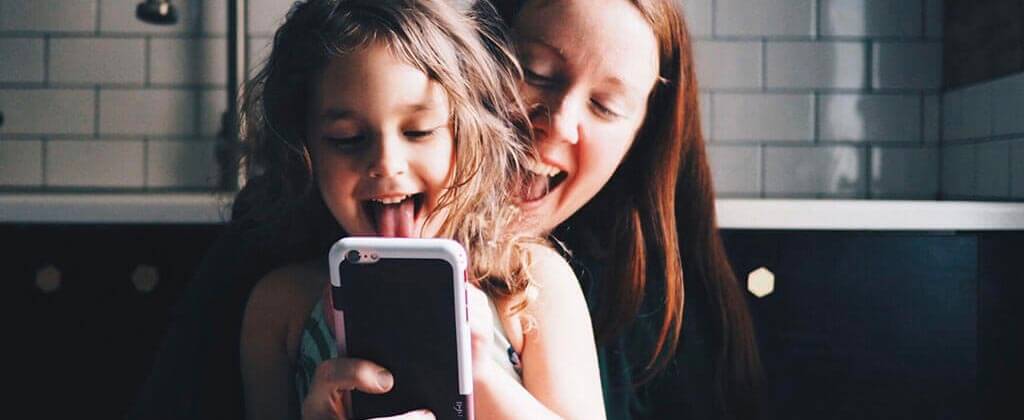 Mom and baby laughing at a smartphone